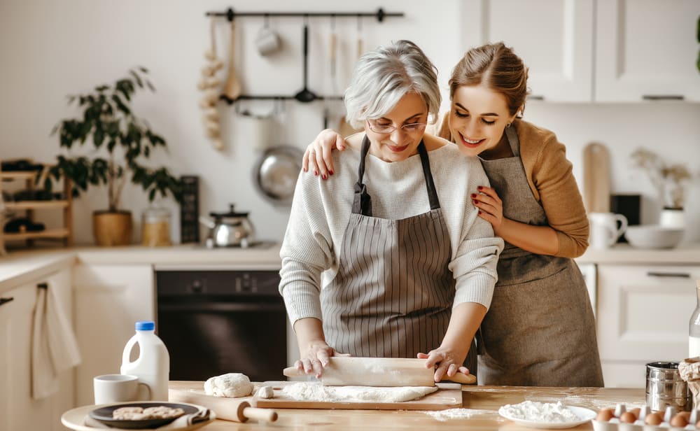 Mother and daughter in apron kneading dough.