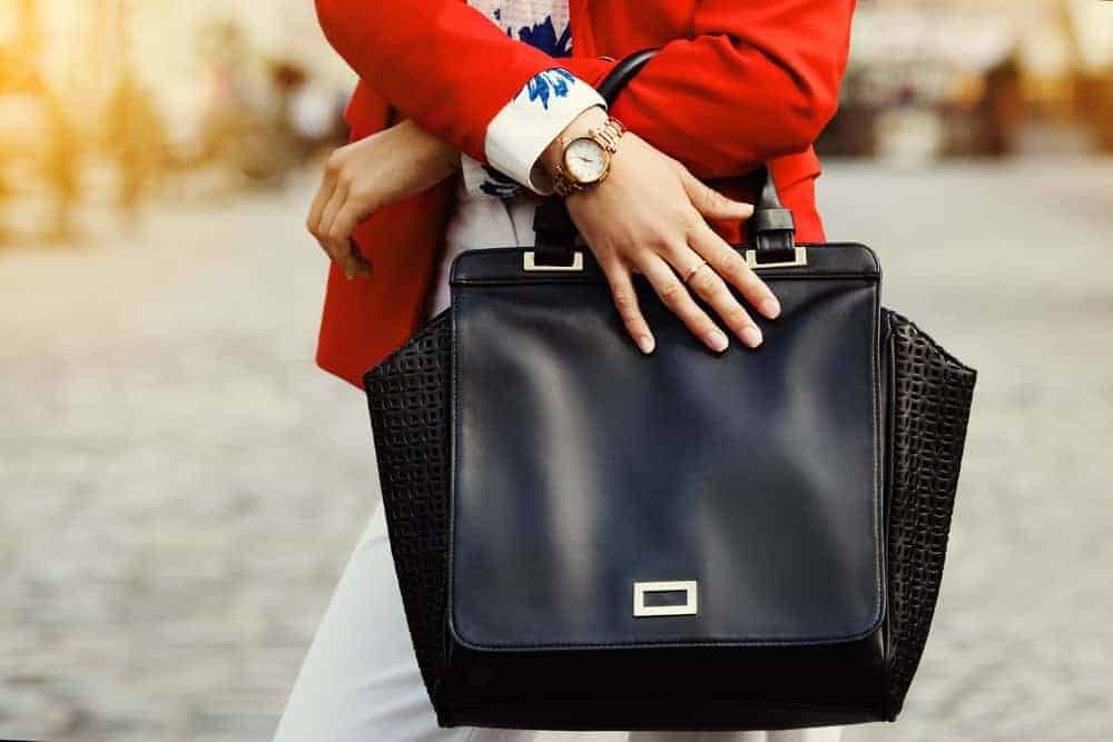 Women carrying a black leather accordion handbag.