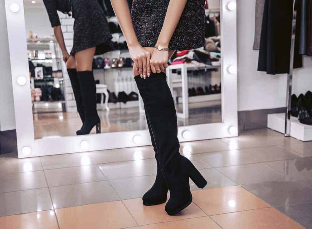 A lady fitting a boot in a shoe store.