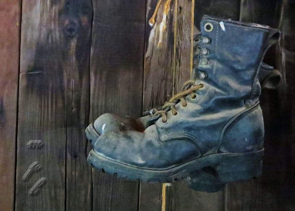 Caulk boots hanging from the end of a wooden bed.