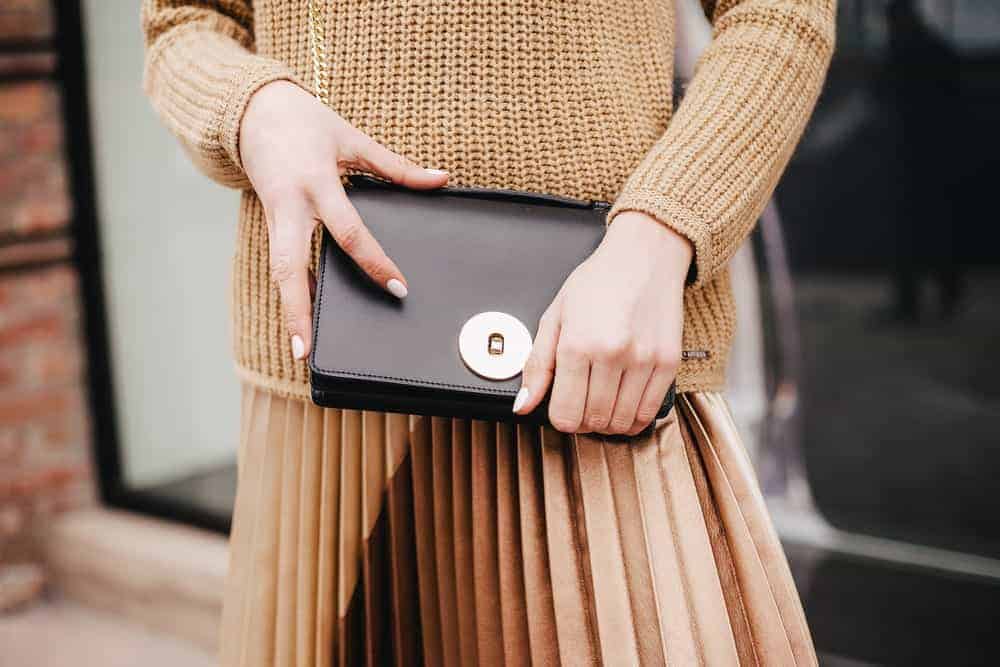 Woman holding a black leather clutch.