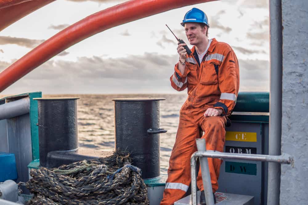 Marine deck officer on deck holding a walkie-talkie.