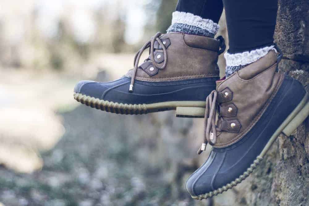 A closeup of a kid's feet wearing duck boots and frilly socks.