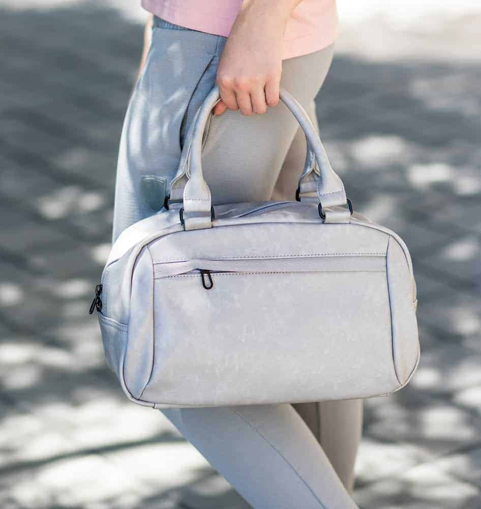 Woman holding a gray duffel bag.