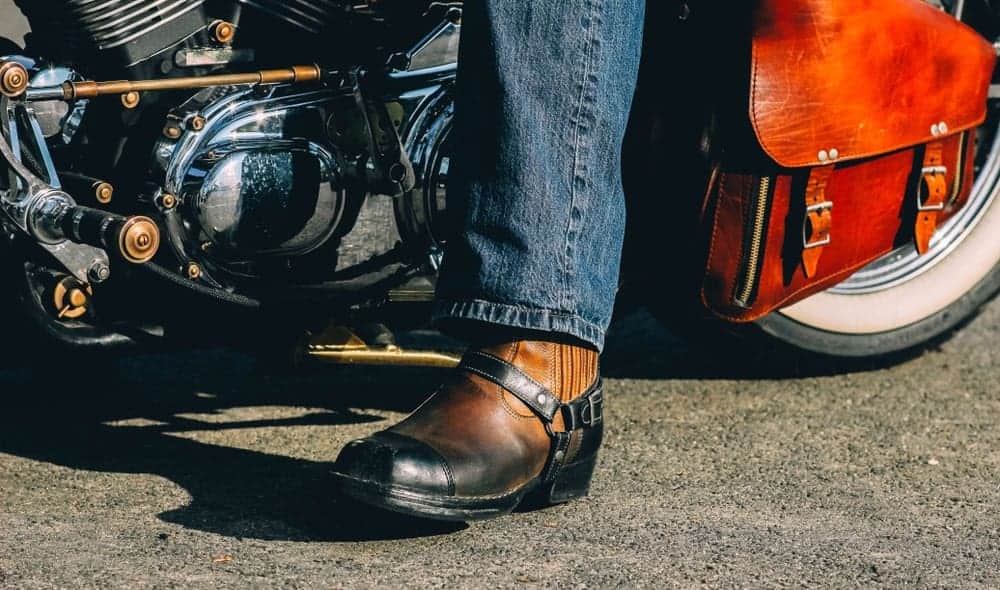 A biker on a retro chopper motorcycle wearing harness boots.