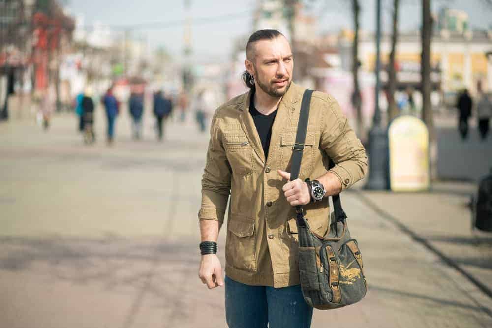 Man with a messenger bag walking on the street.