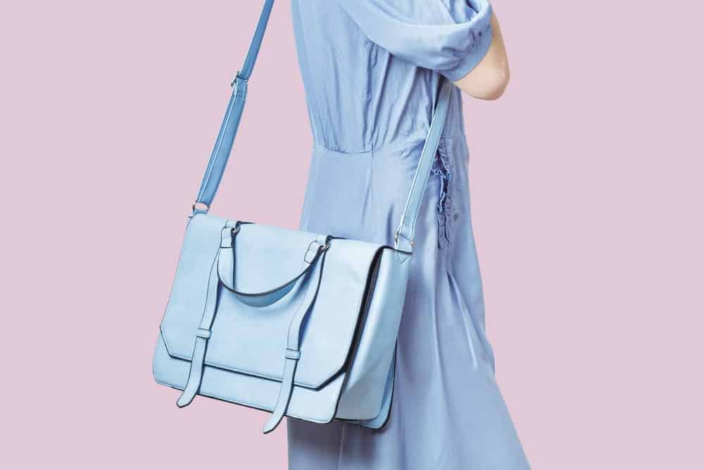 Woman in light blue dress with matching messenger bag.