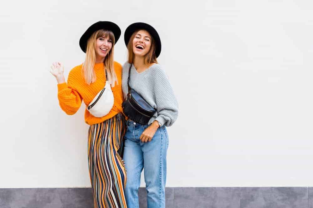 Hipster women wearing puffed sweaters and black hats.
