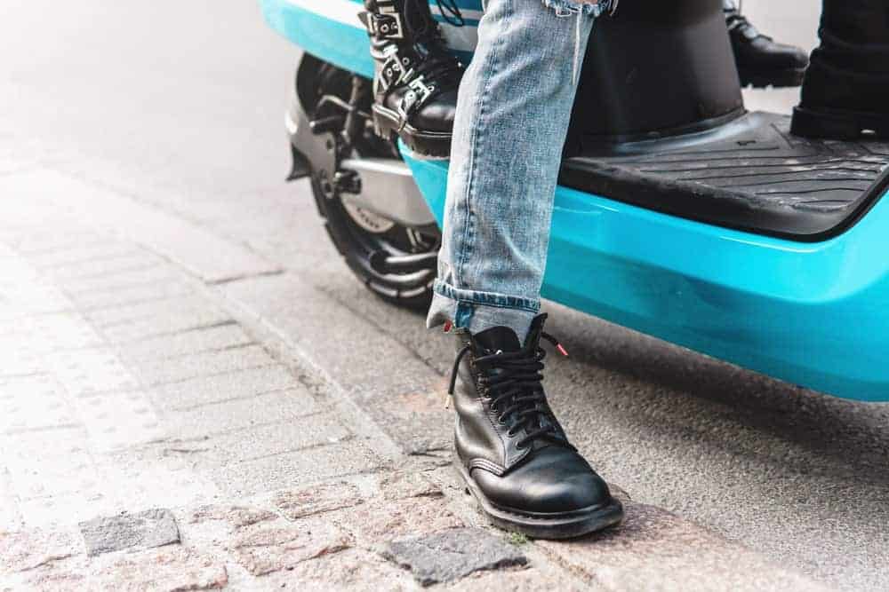 A couple in service boots riding a motorcyle.