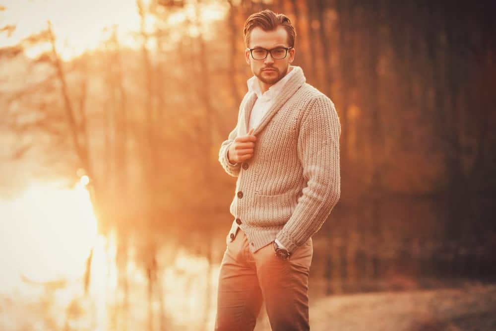 Man in an autumn scene wearing a shawl neck sweater.