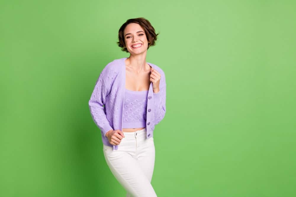 Woman in a purple twinset sweater flashing a sweet smile.