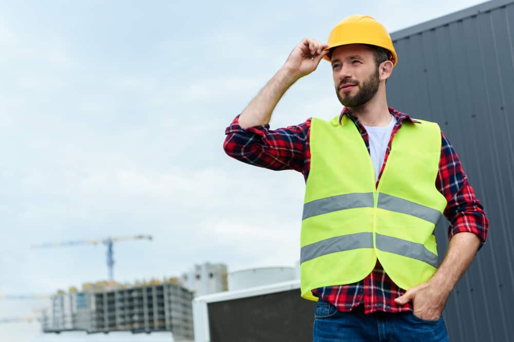 Engineer in safety vest and helmet posing on roof.