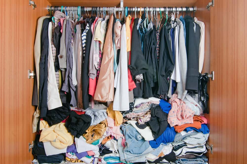Wardrobe filled with pile of clothes.