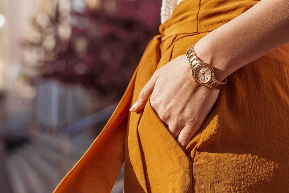 Woman in orange dress with gold watch.