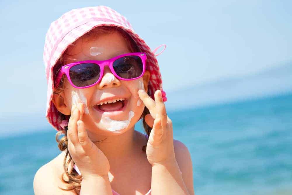 A kid wearing a beach hat at the beach.