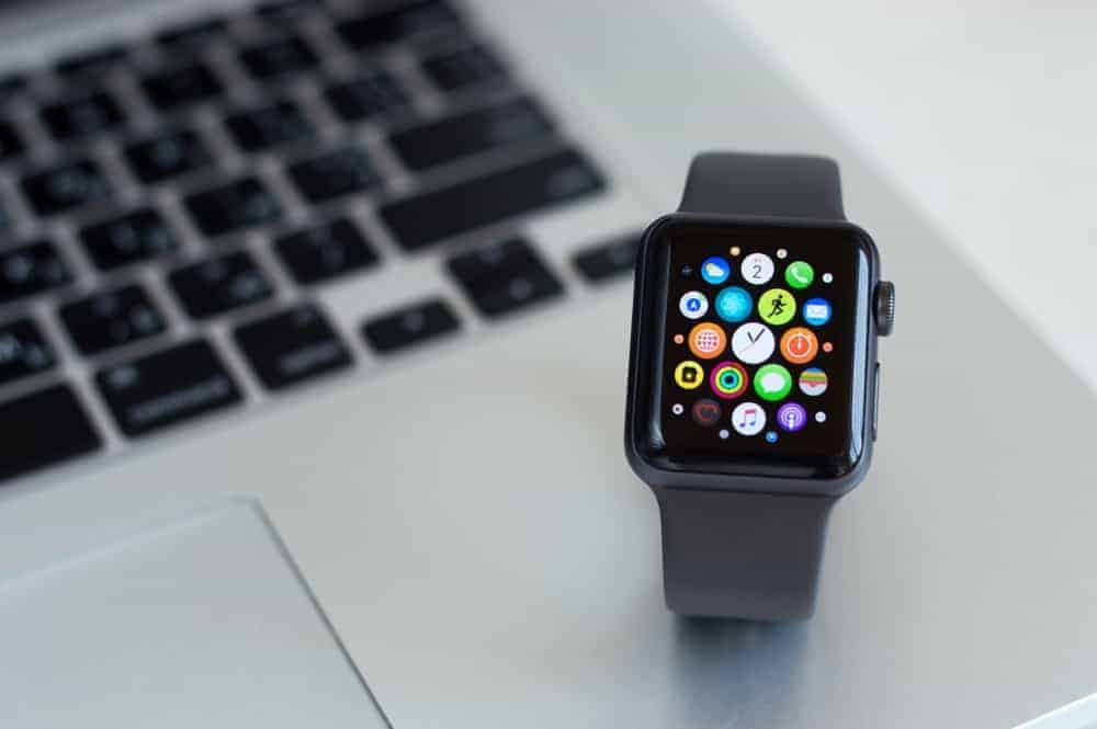 An Apple watch with gray straps on a laptop.