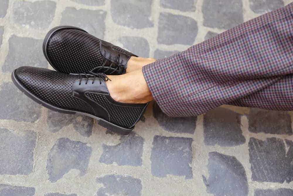 A close look at a man wearing a pair of checkered pants to match his summer shoes.
