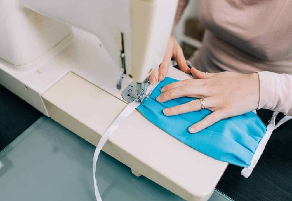 A woman making face masks with the use of a sewing machine.