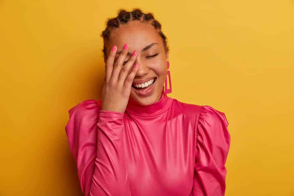 A close look at a woman wearing a bright pink long sleeve blouse.