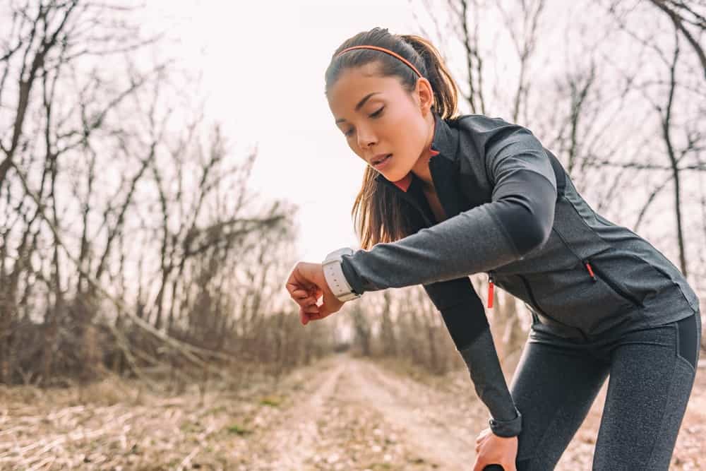 A female jogger checking her smartwatch health tracker.