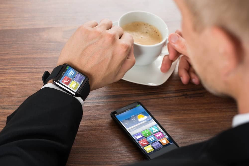 A businessman syncing his smartwatch with his phone apps.