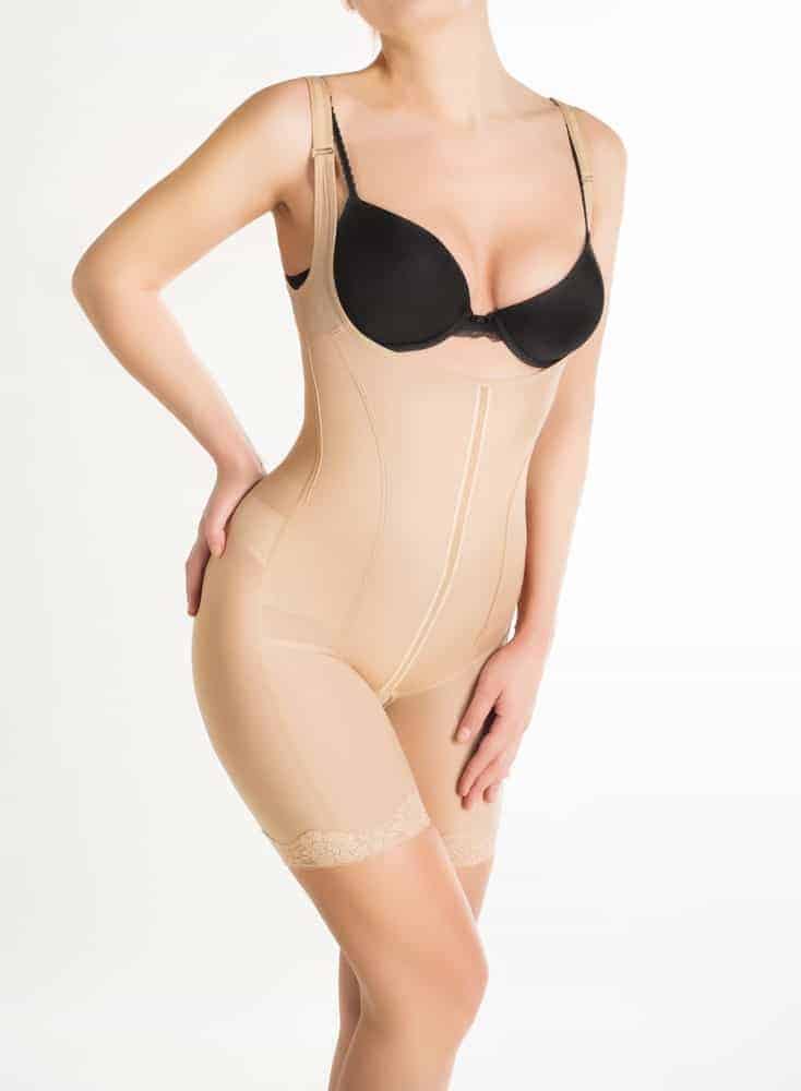 A woman wearing a skin-tone shapewear with her black bra.