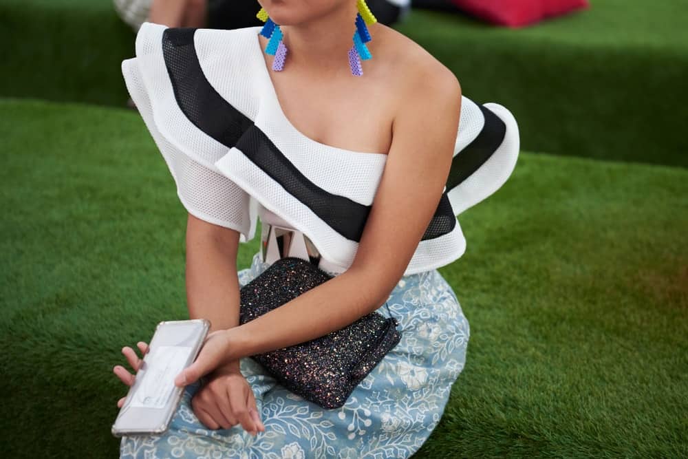 A woman wearing fashionable clothes that make her colorful statement earrings stand out.