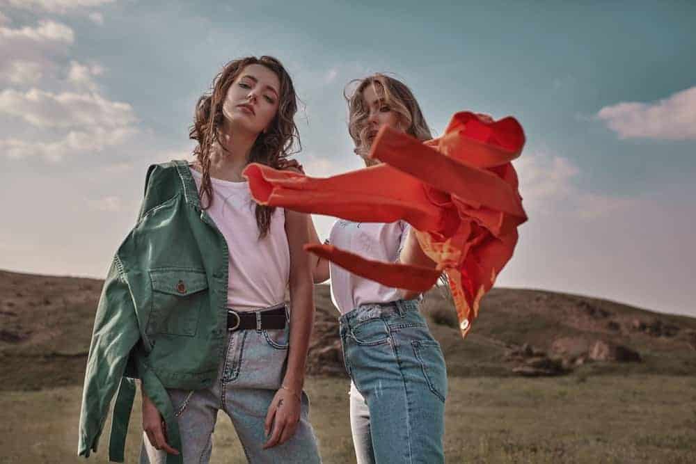 A couple of women wearing trendy jackets and jeans.