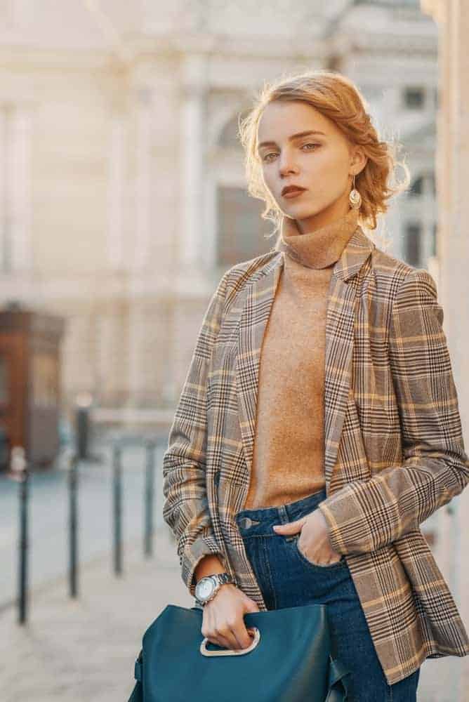 A woman wearing a pair of jeans with her plaid jacket.