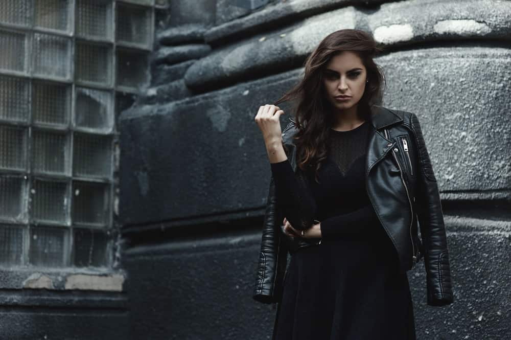 A woman wearing a black dress with her black leather jacket.