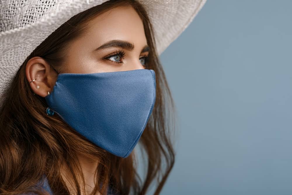 A woman wearing a blue mask to pair with her long hair and white hat.