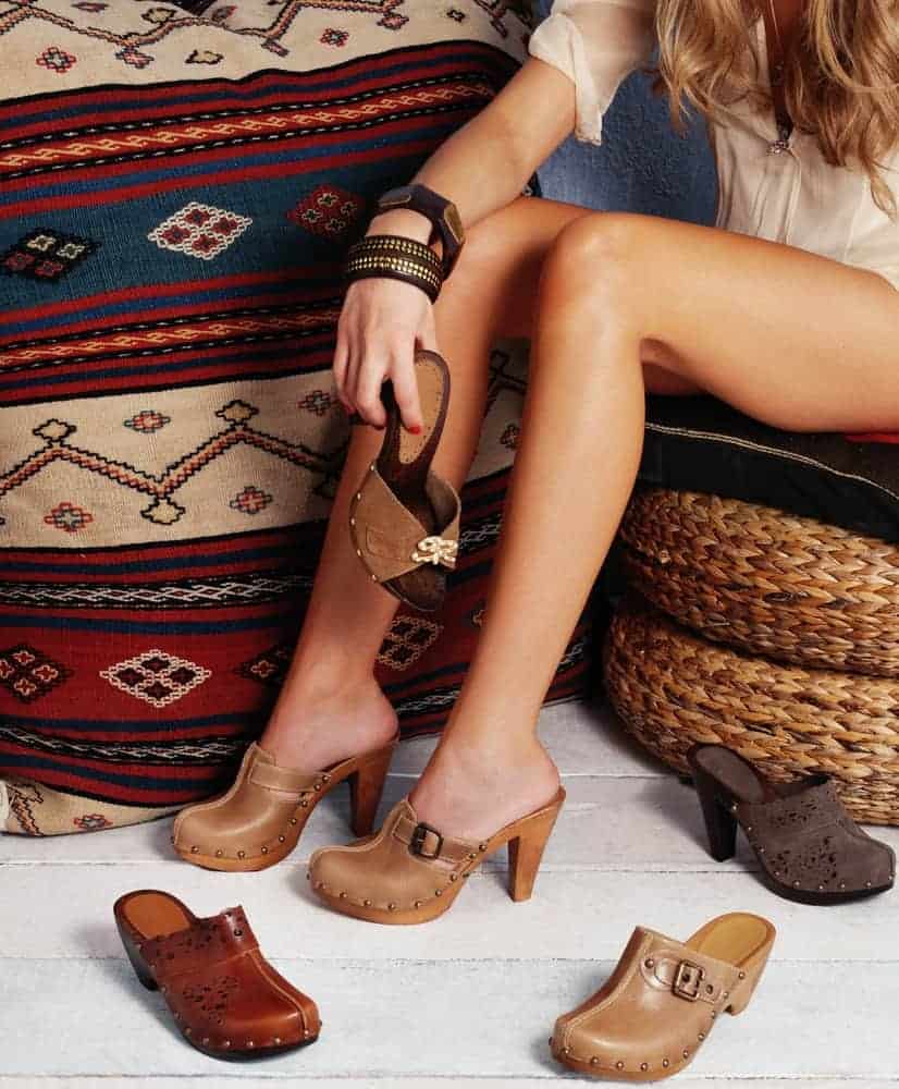 A woman trying on different pairs of modern clogs.