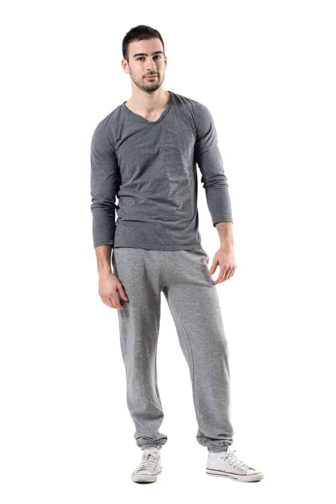 A man wearing gray sweats with white sneakers.