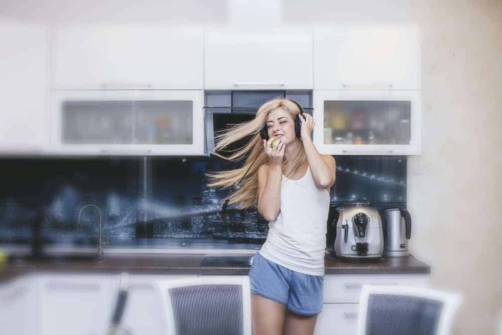 A woman dancing around in her kitchen wearing loungewear.