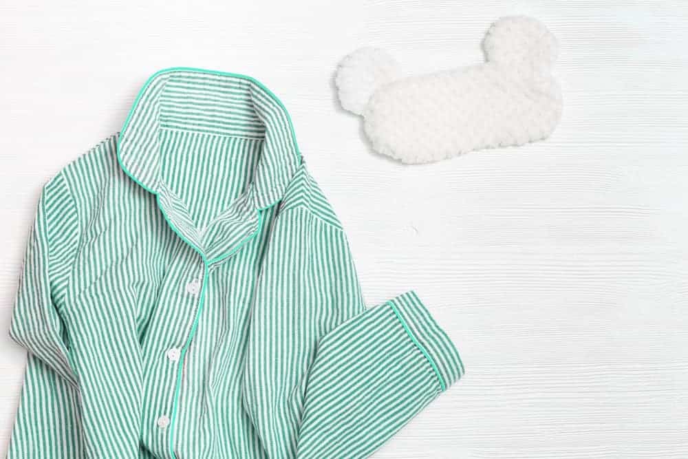 A pair of mint-colored pajamas with a white sleeping mask.