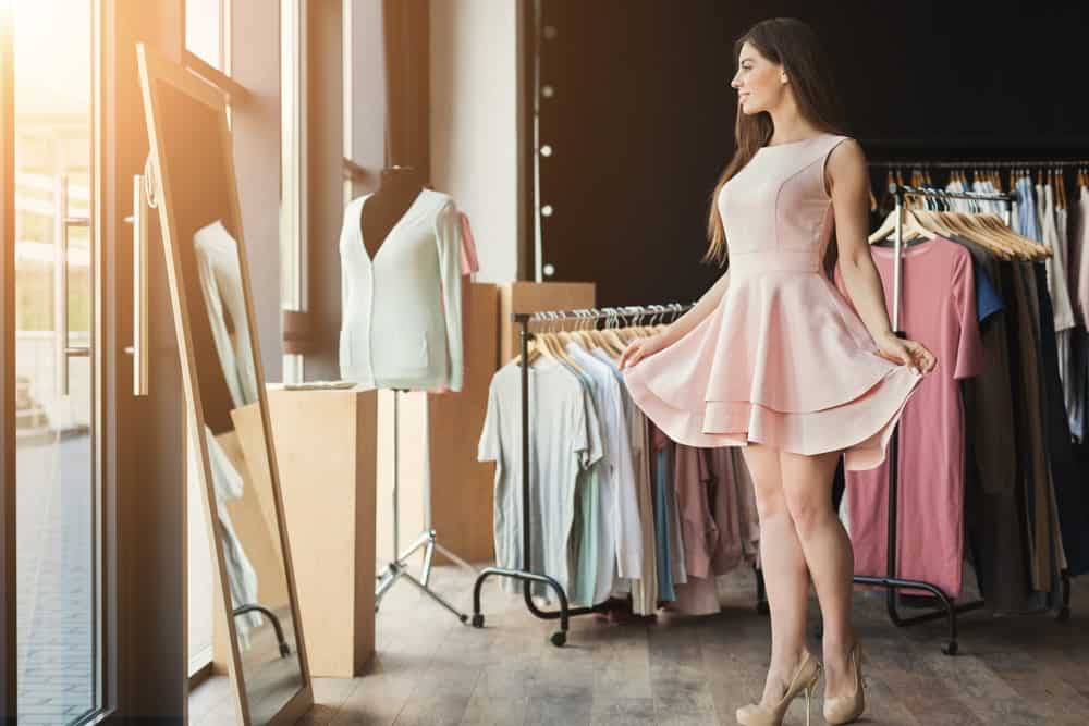 A woman trying on a pink dress at the store.