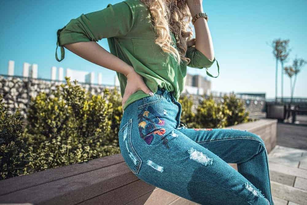 A woman wearing a pair of jeans and green blouse at the park.