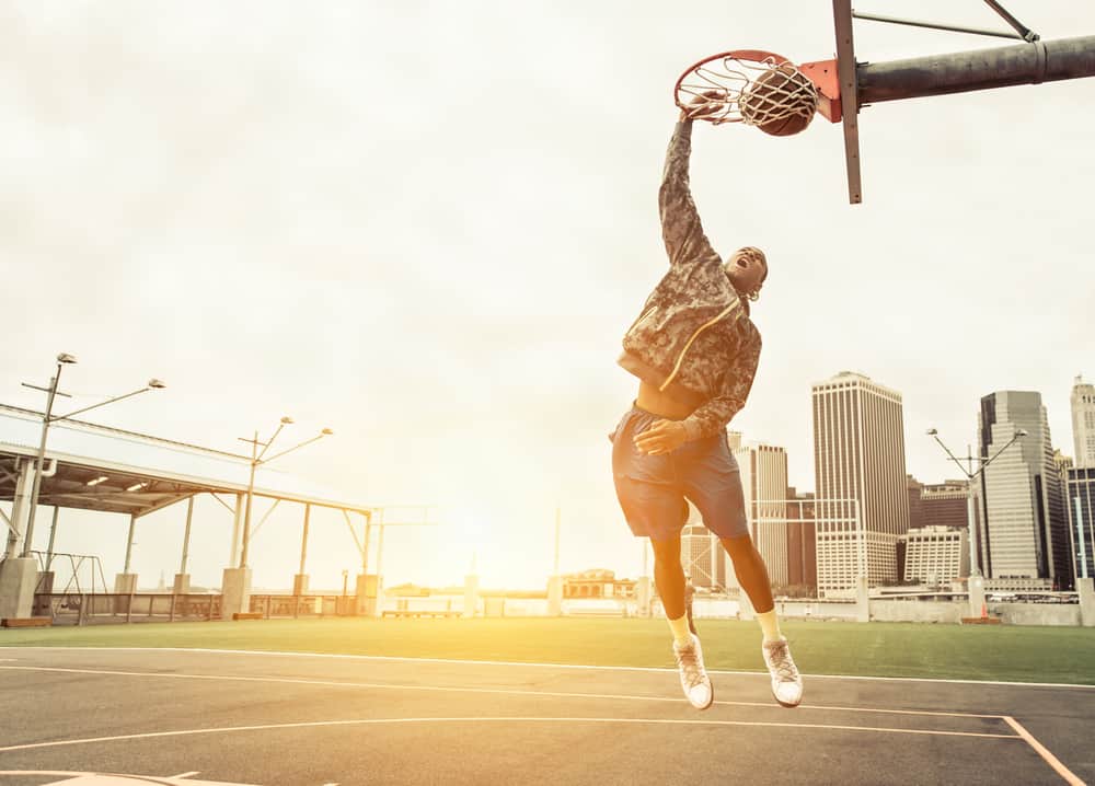 Street basketball player performing power slum dunk.