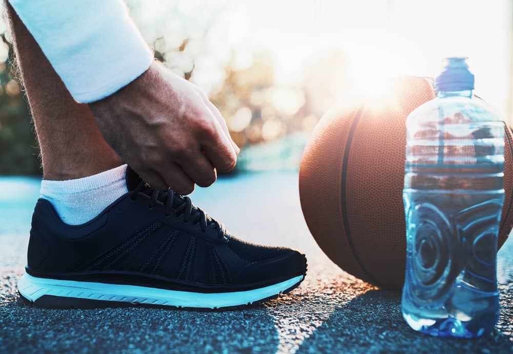 Basketball player tying his low-top basketball shoe.