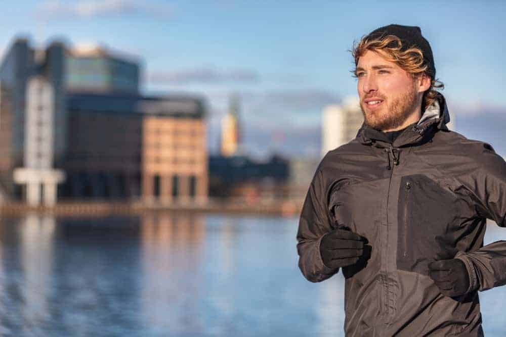 A man jogging while wearing a coat.