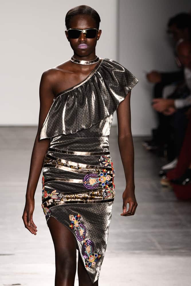 A model in an asymmetrical dress walks the runway.