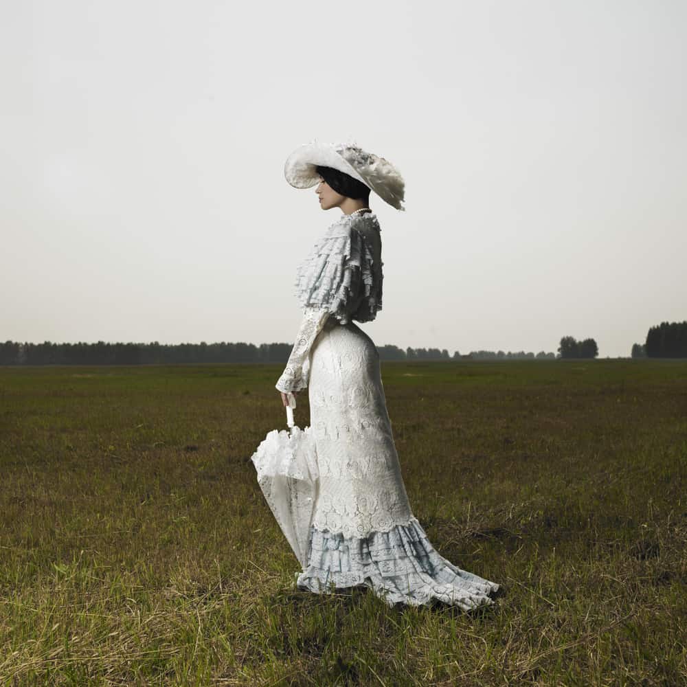 Woman wearing a Victorian dress with matching hat and umbrella.
