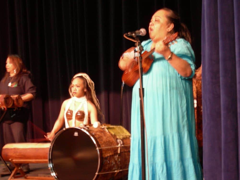 Woman in a blue muumuu dress performing on the stage.