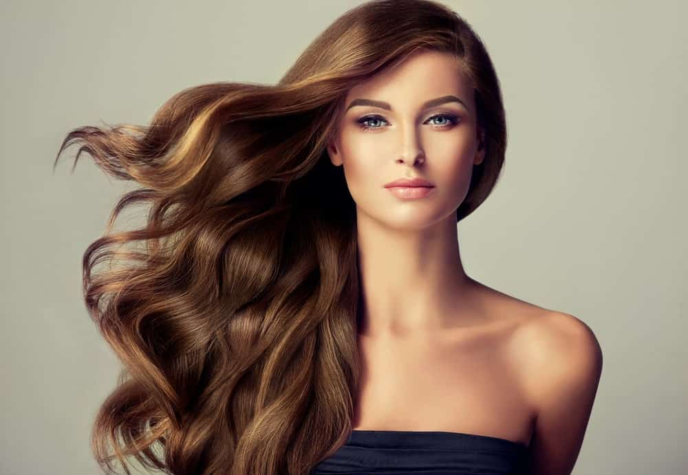 A woman wearing a long and wavy brunette wig.