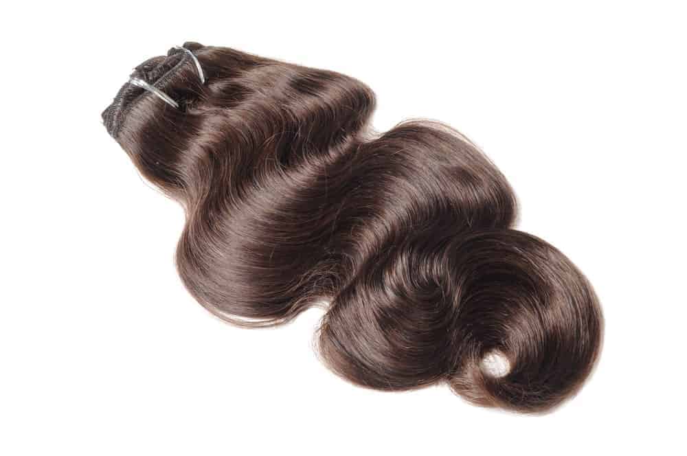 Clip-in body hair extension in wavy, dark brown.
