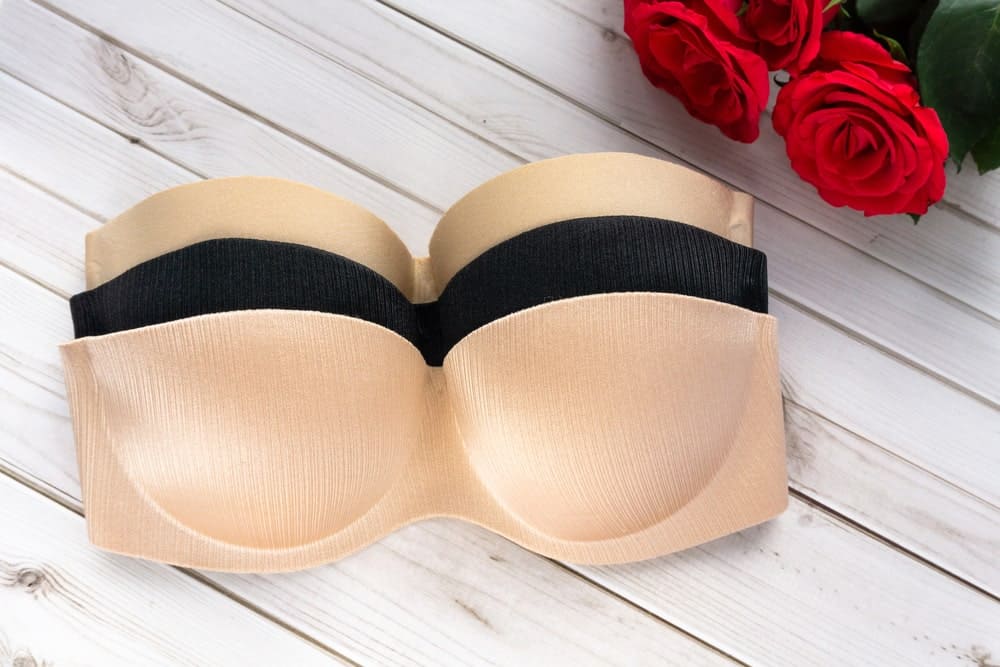 Three strapless bras on a wooden table.