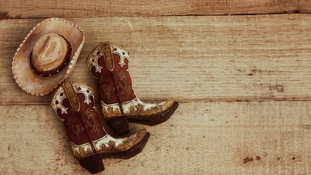 A pair of detailed cowboy boots and a straw hat.