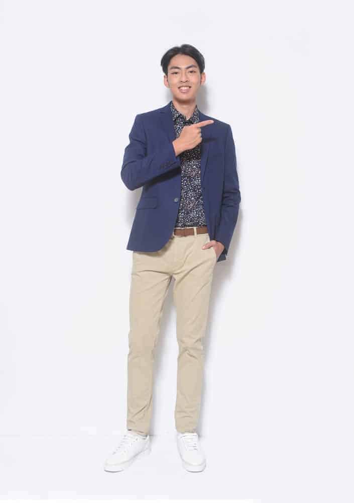 A man wearing a blazer and a pair of classic khaki pants.