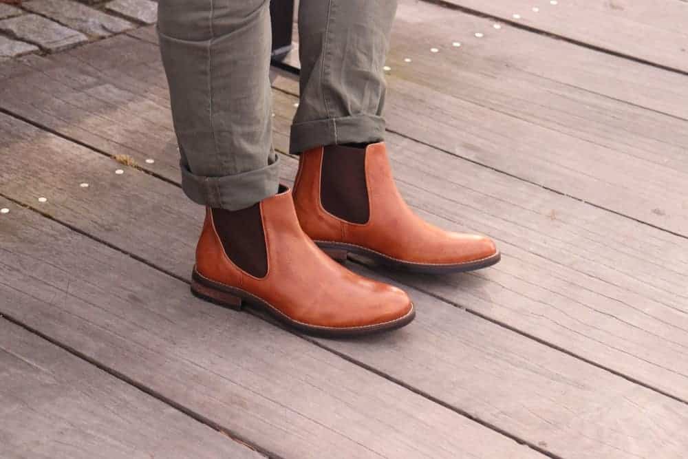 A close look at a man wearing boots and folded khaki pants.
