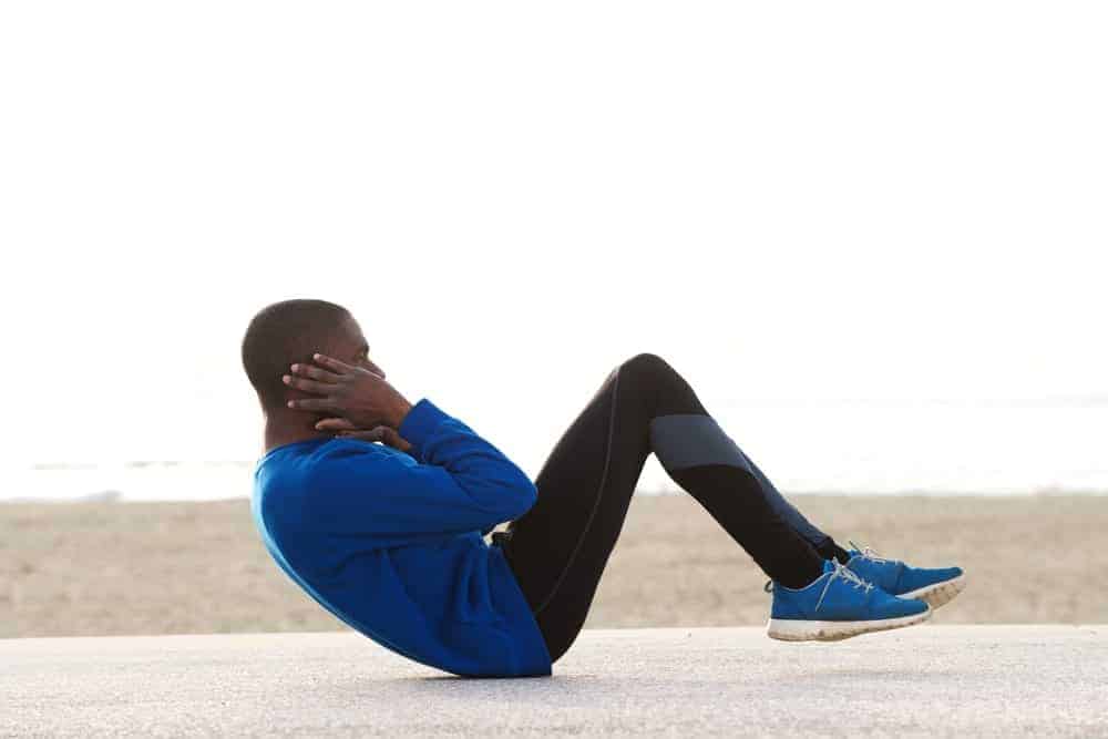 A man doing crunches while wearing leggings.